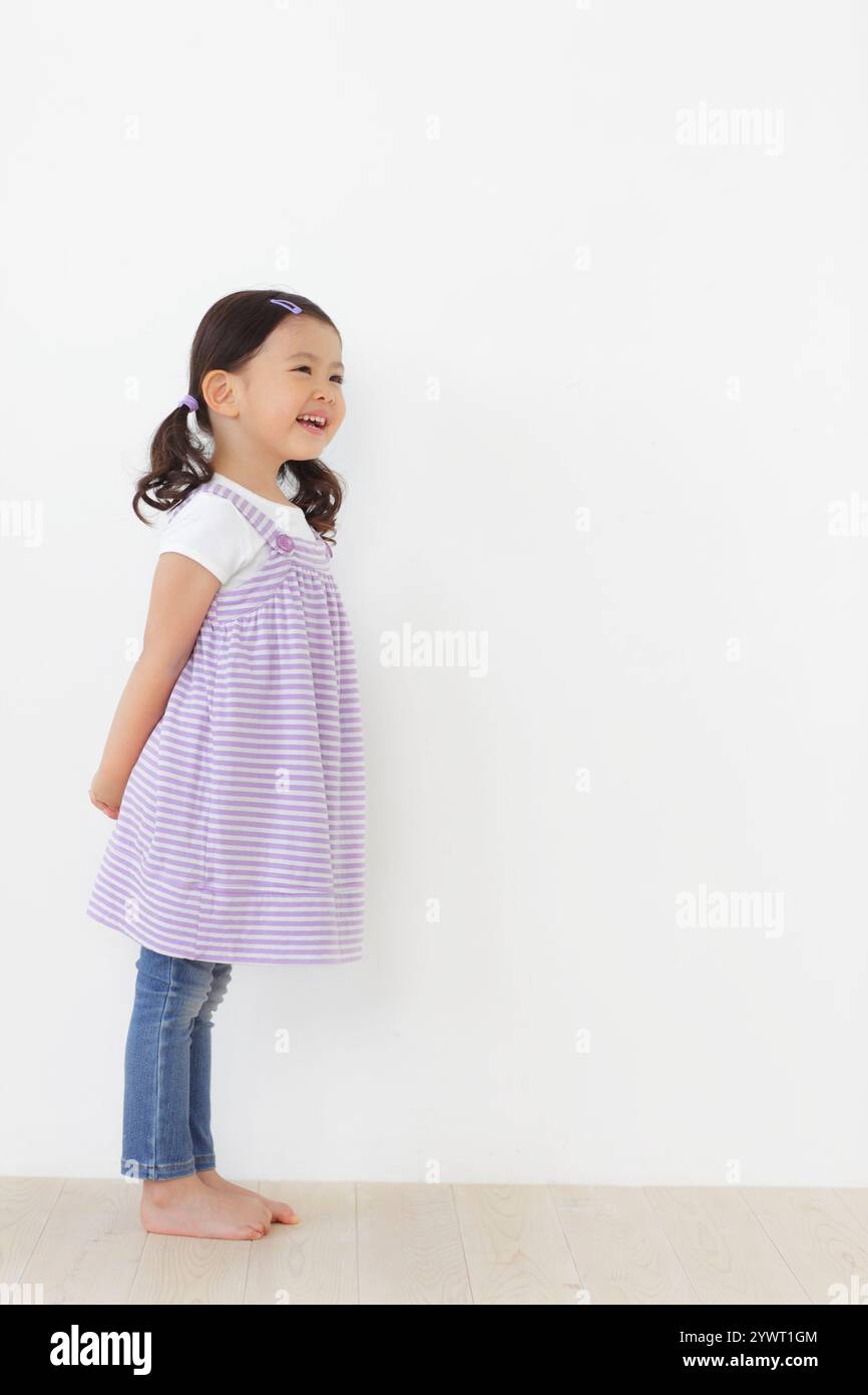 Little girl standing on wooden floor Stock Photo - Alamy