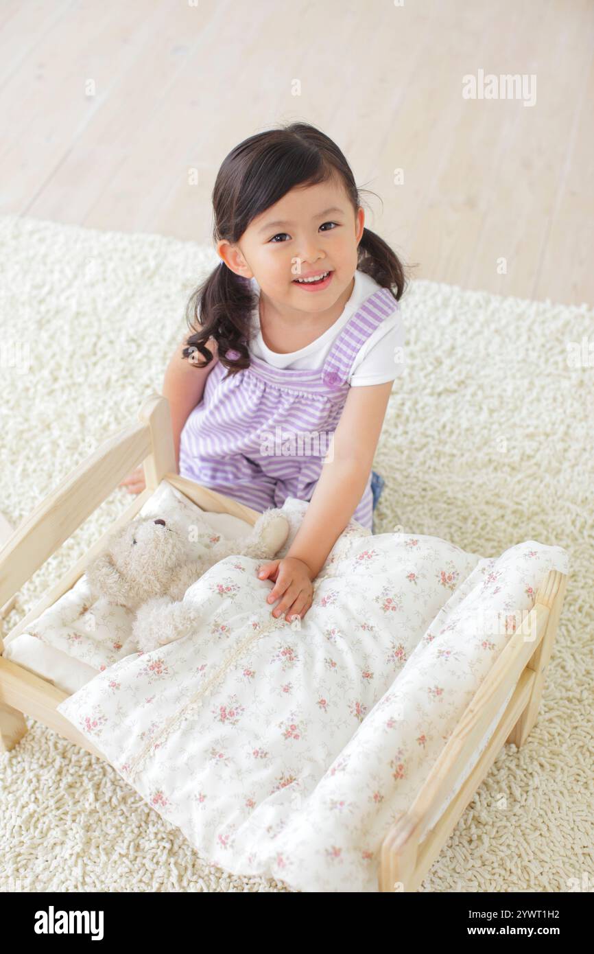Girl playing with stuffed animal on toy bed Stock Photo - Alamy