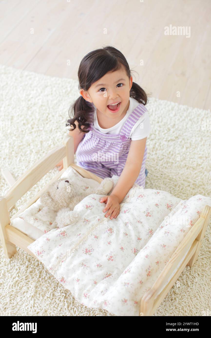 Girl playing with stuffed animal on toy bed Stock Photo - Alamy