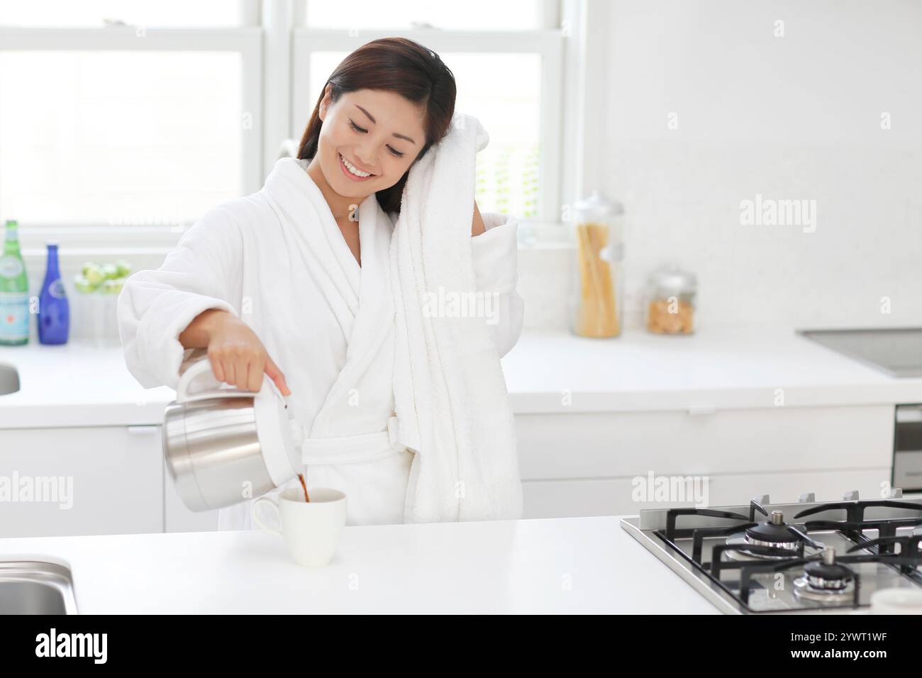 Woman pouring coffee in kitchen after bathing Stock Photo