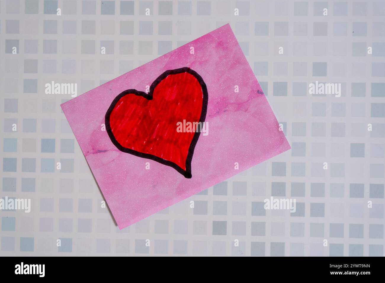 A red love heart drawn on a sticky note or post-it stuck on a wall Stock Photo