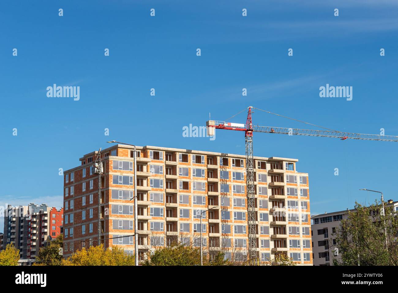 Сonstruction of a multi-storey residential building on a sunny day. Brick house under construction and tower crane against blue sky. Сonstruction site Stock Photo