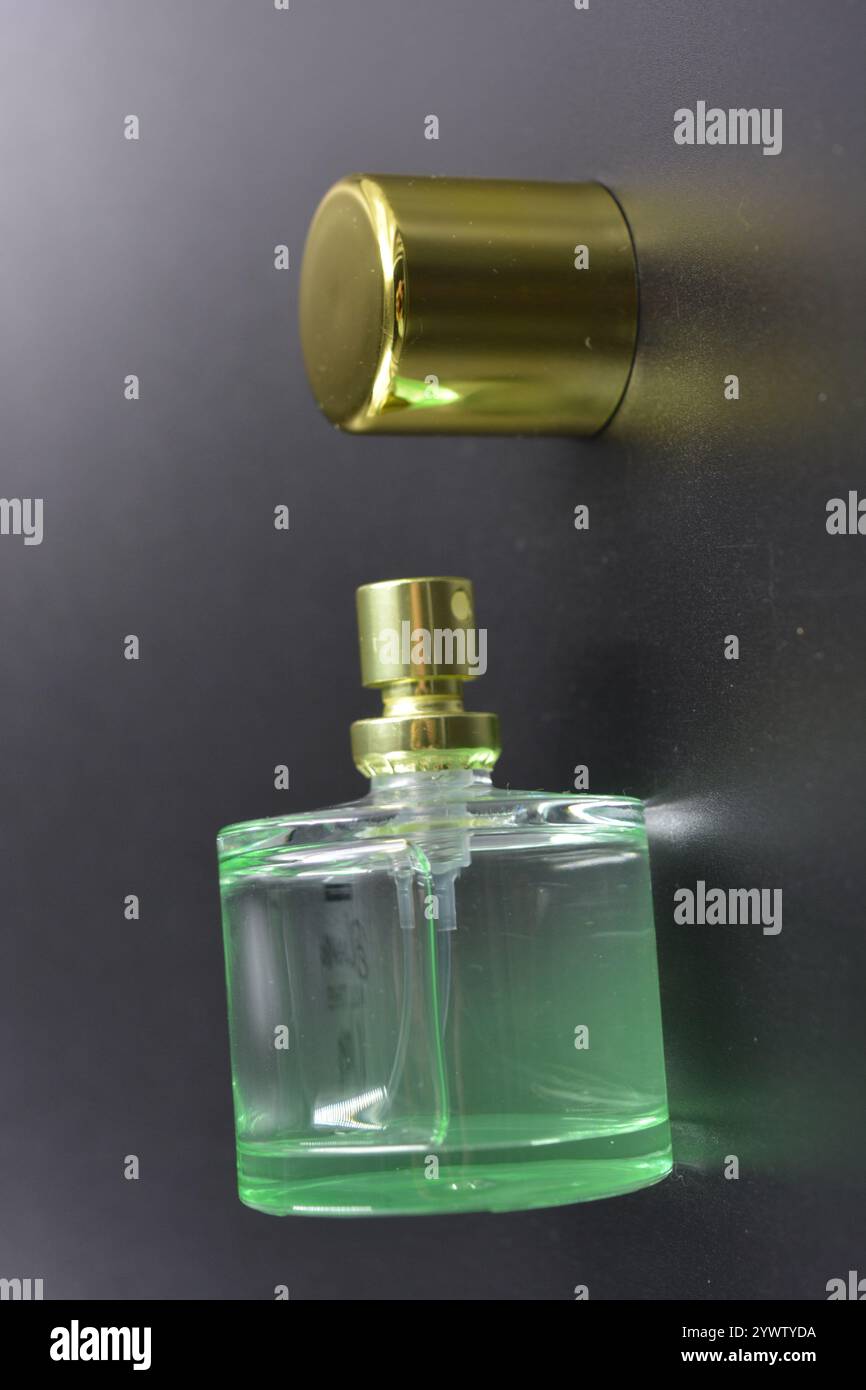 Women's clothes, perfumes, pleasant aromas. Glass bottle with green liquid perfume, gold plastic cap and gold spray dispenser. Stock Photo