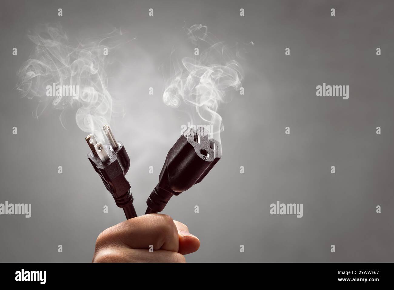 Hand holding the smoking ends of a power cord Stock Photo