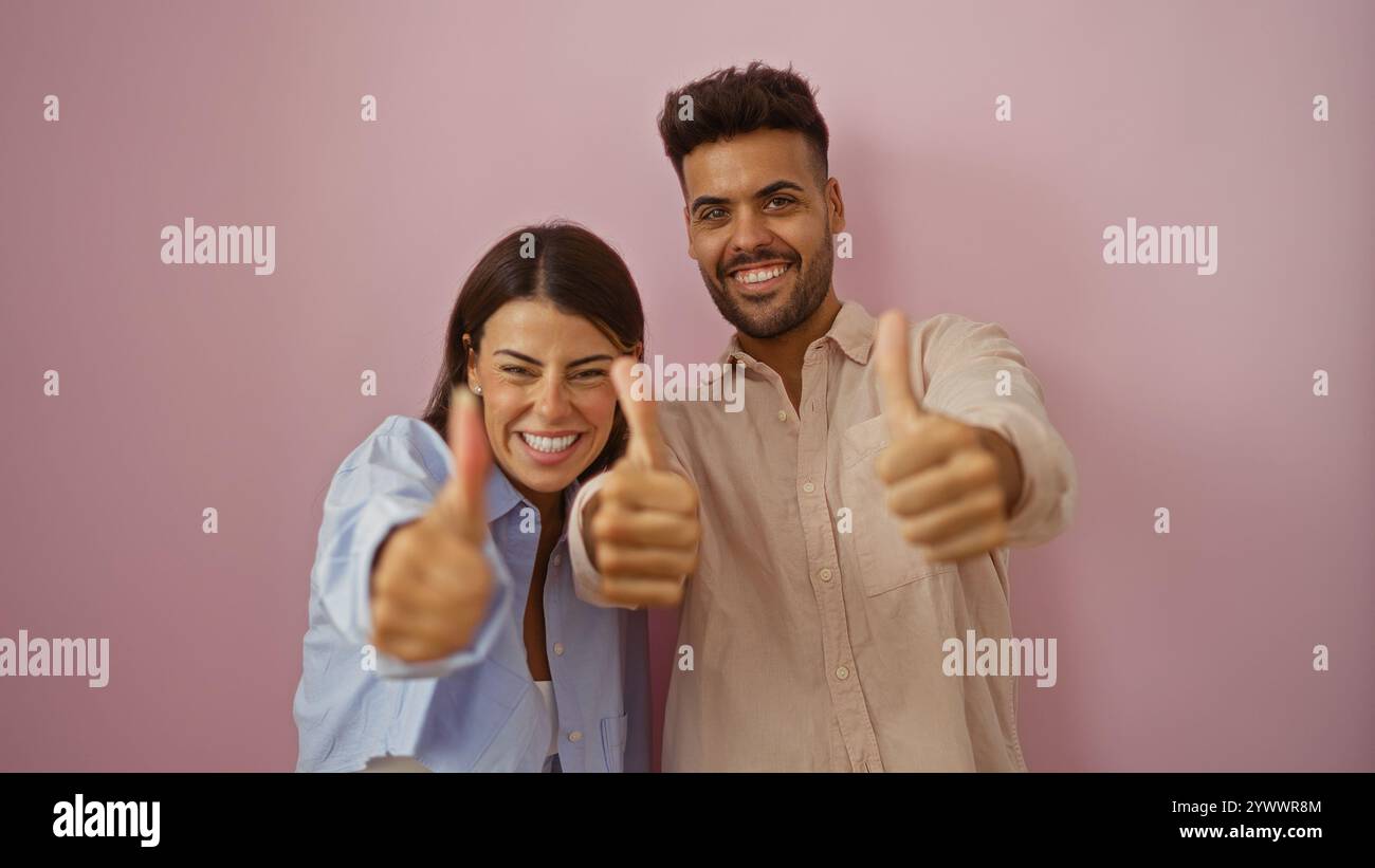 Happy couple smiling and giving thumbs up against a pink background ...