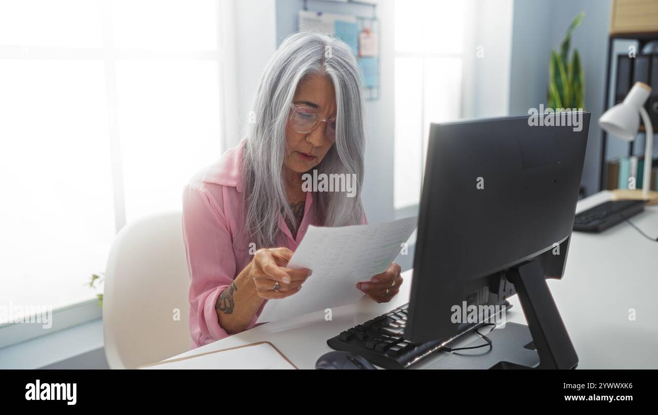 Elderly woman with grey hair working at a computer in an office ...