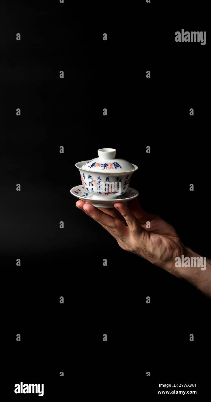 An Elegant Handheld Teacup Displayed Against a Dark, Striking Background for Visual Appeal Stock Photo