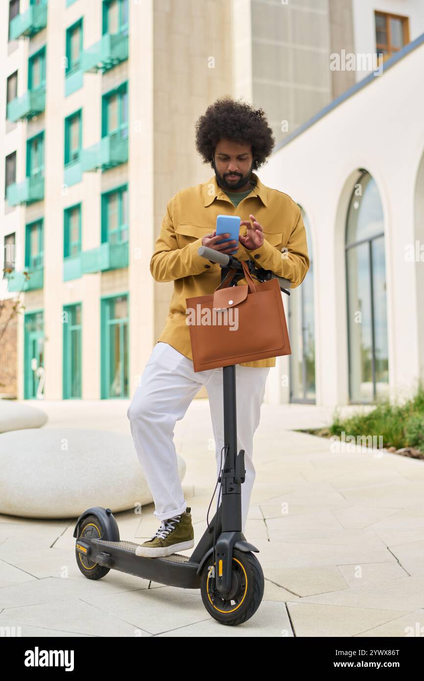 Man Using Smartphone While Standing on Electric Scooter Stock Photo