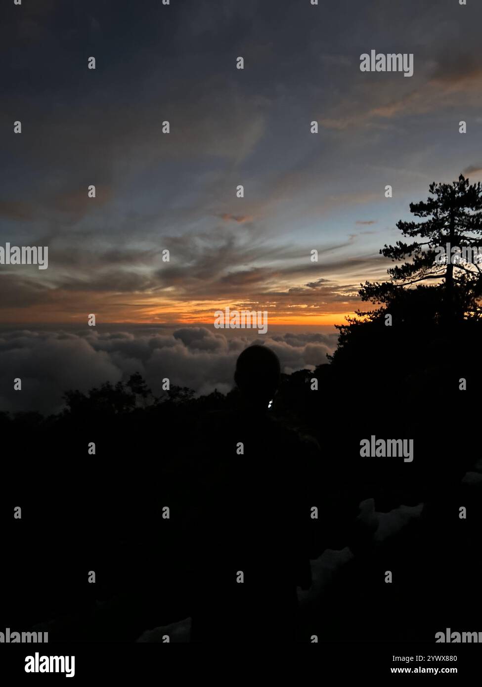 Silhouette of a Person Overlooking Dramatic Sunset Above the Clouds with Colorful Sky and Forested Mountain Edge Cyprus Ayia Napa - Smartphone Captured Stock Image