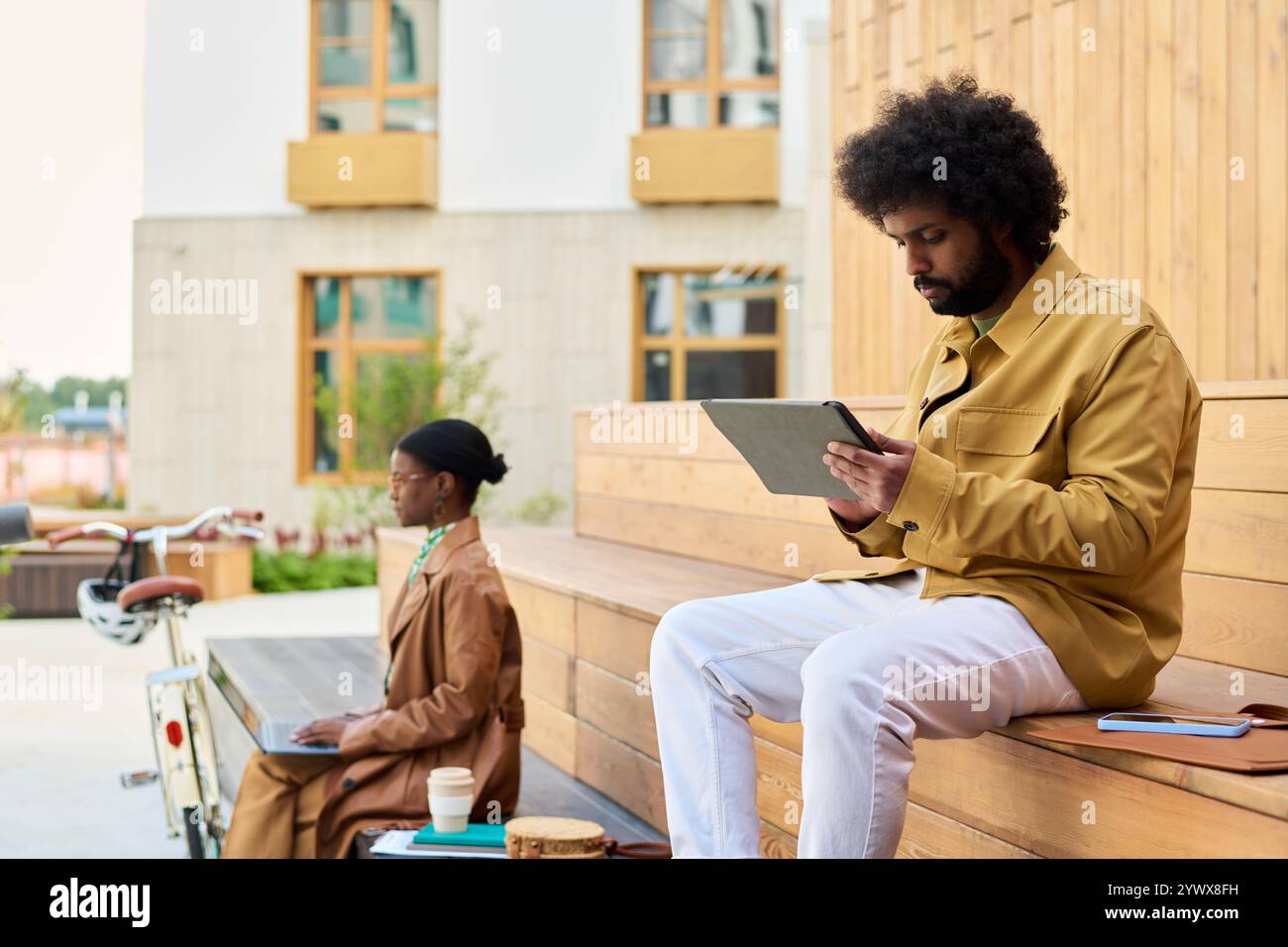 Man Using Tablet While Sitting on Wooden Bench Stock Photo