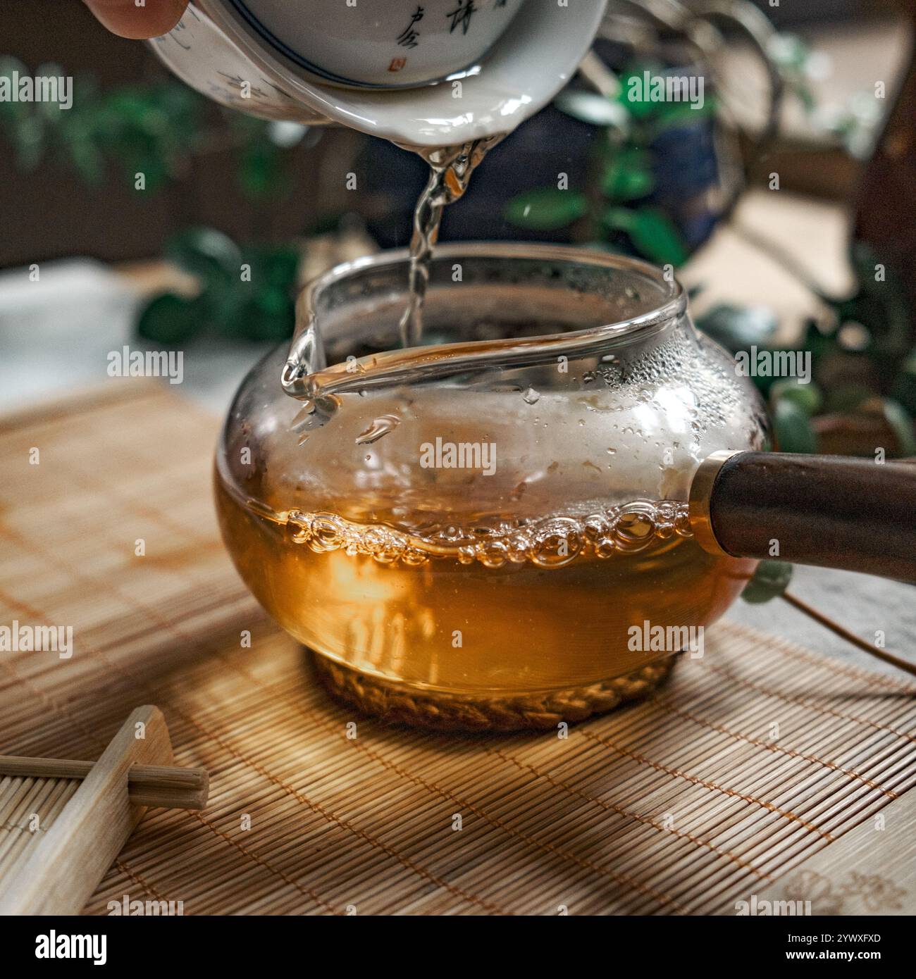Tea is poured into a beautiful glass teapot, releasing delicate steam ...