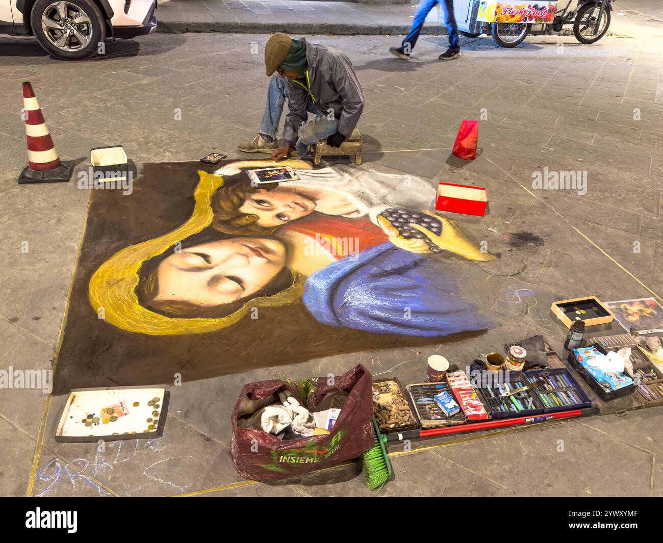 An artist reproduces classic paintings with chalk on the flagstones of a street in Florence, Italy, working only for tips.  The drawings are cleaned o Stock Photo