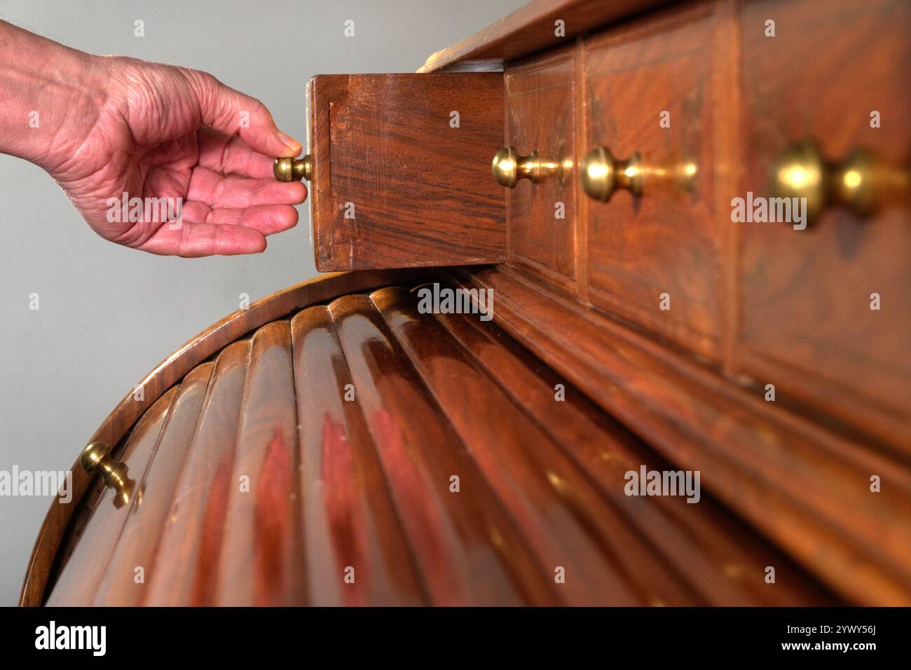 Closeup of a man’s hand pulling open one of the drawers of an ornate ...
