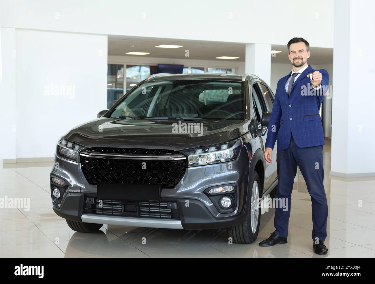 Happy salesman holding key near new black car in salon Stock Photo - Alamy