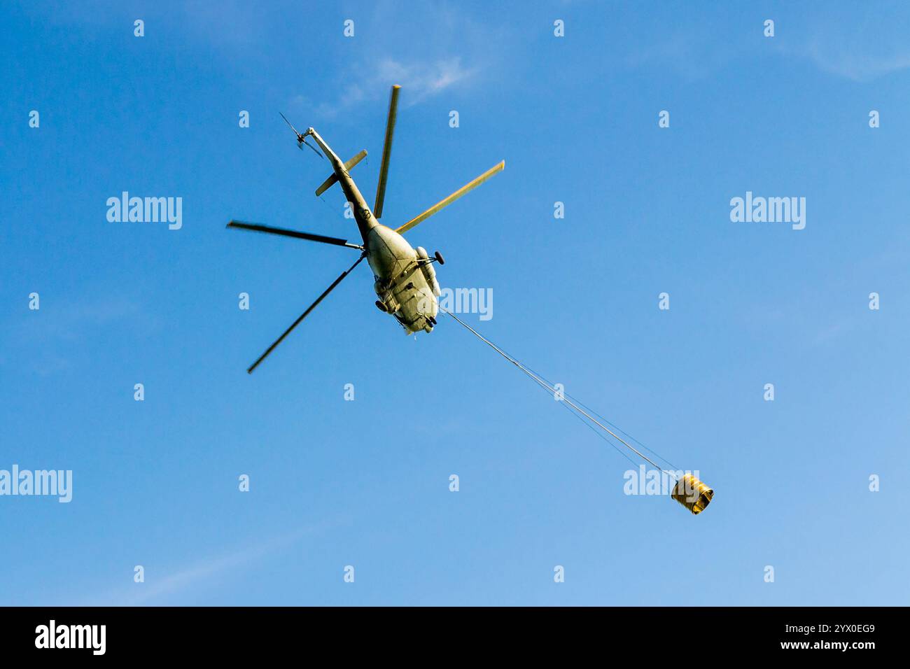 Helicopter in action carrying the water bucket. Shot from the below. Stock Photo