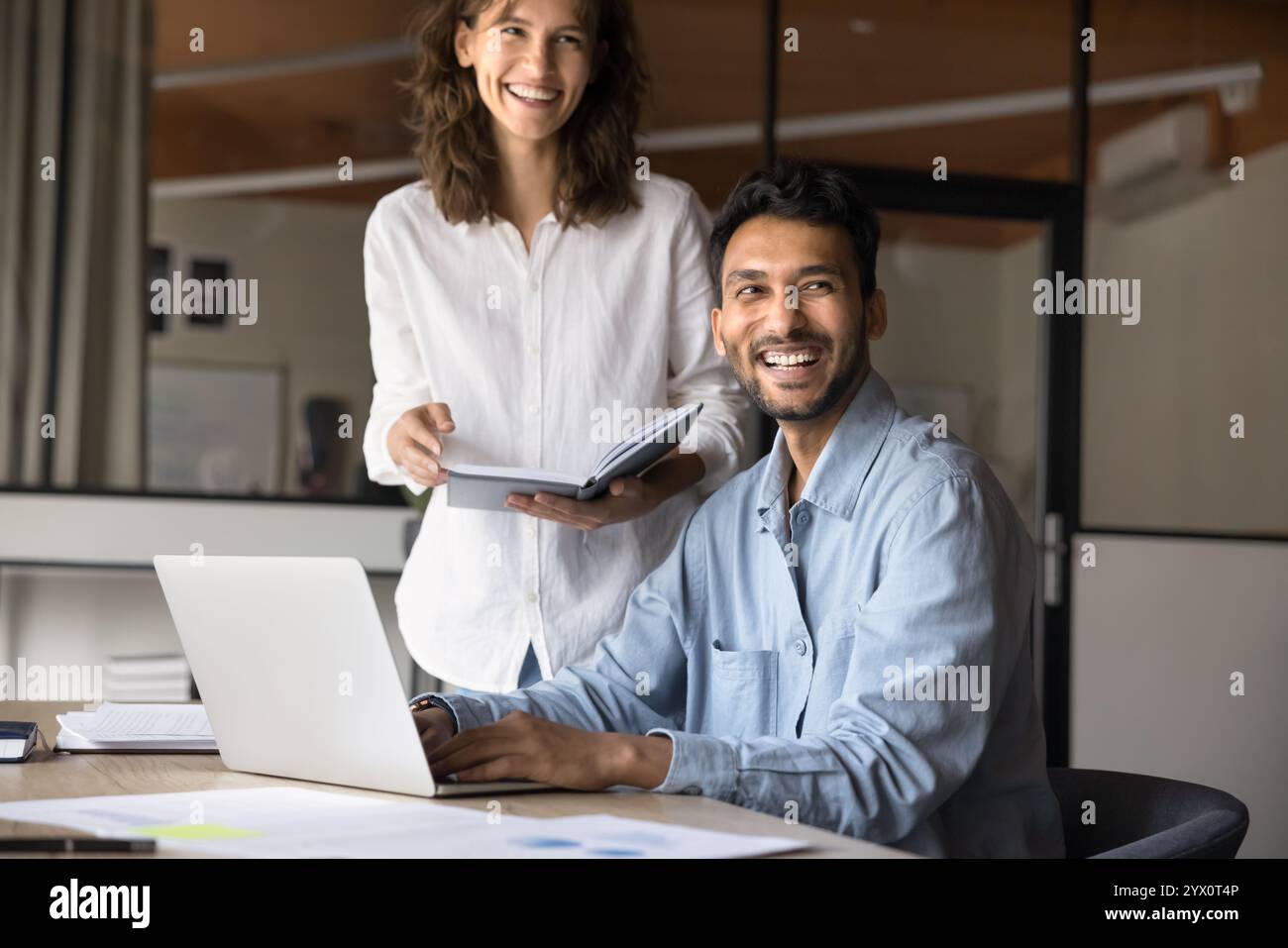 Two joyful Hispanic and Indian teammates working on joint task Stock Photo