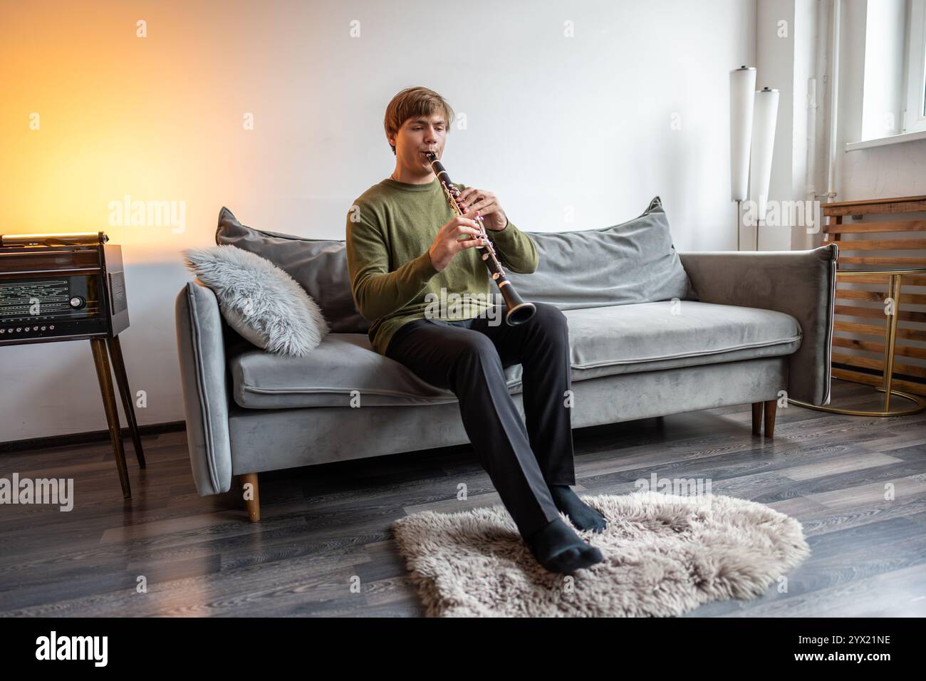 Clarinet player. Clarinetist playing flute woodwind music instrument at home. Guy plays oboe Stock Photo