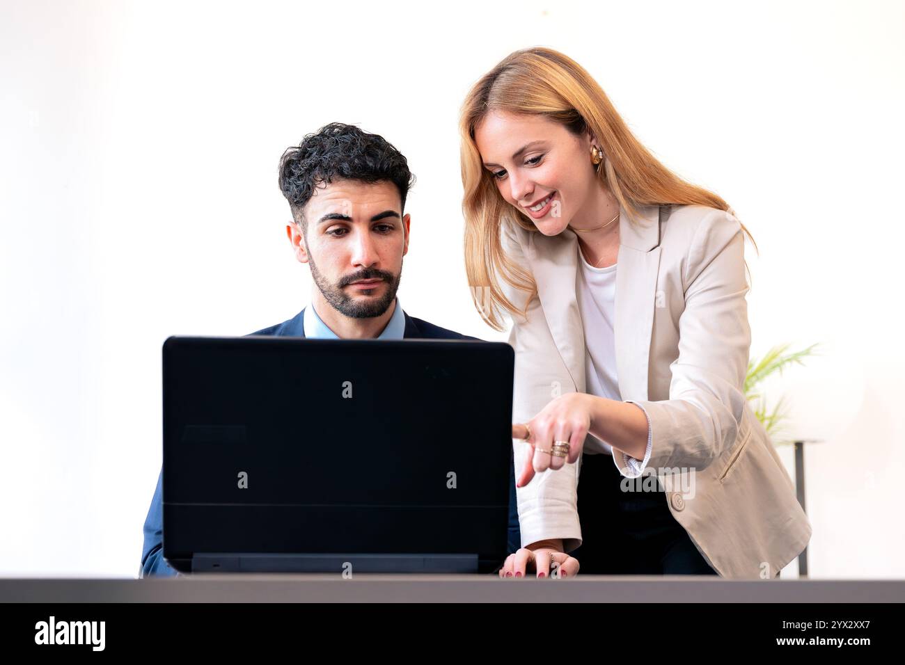Colleagues Collaborating on Laptop in Bright Office Setting Stock Photo