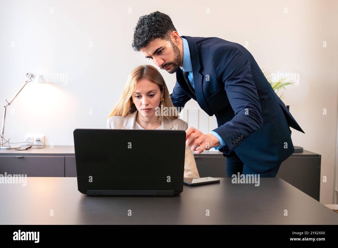 Colleagues Collaborating on Laptop in Bright Office Setting Stock Photo