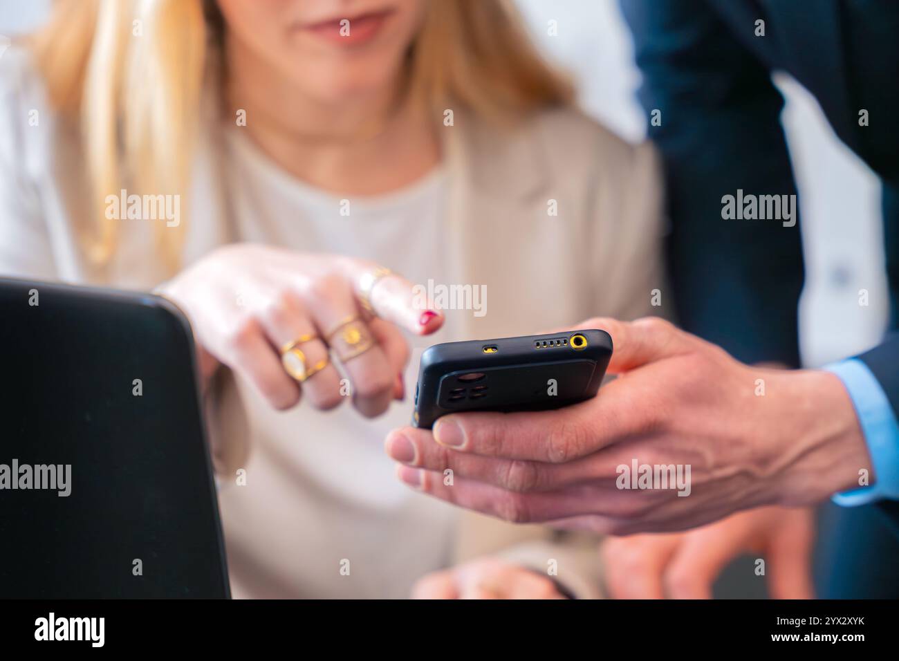 Unrecognizable colleagues discussing work while using a smartphone in the office Stock Photo