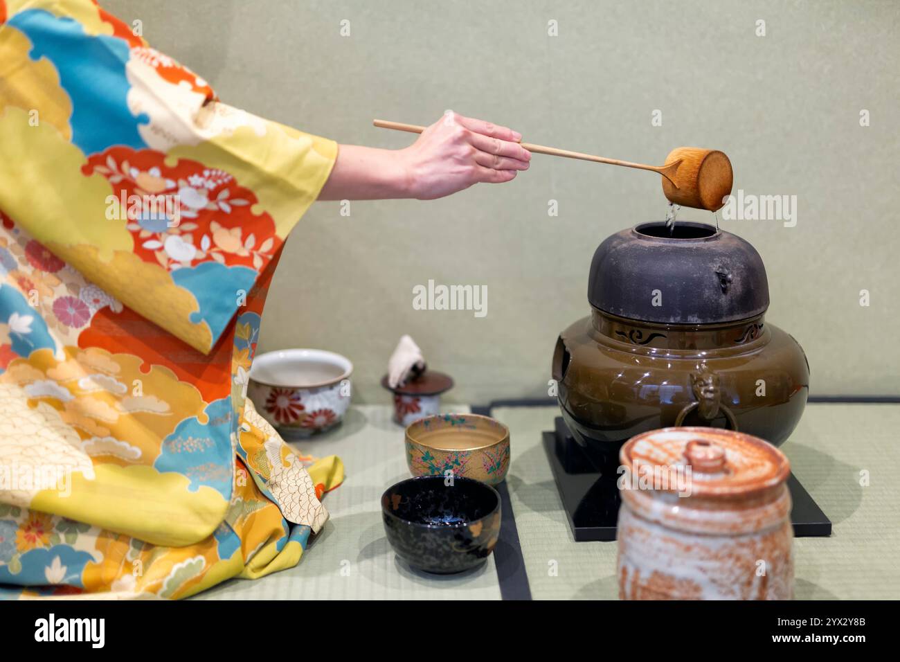Woman in yellow kimono is going to start tea ceremony. Stock Photo