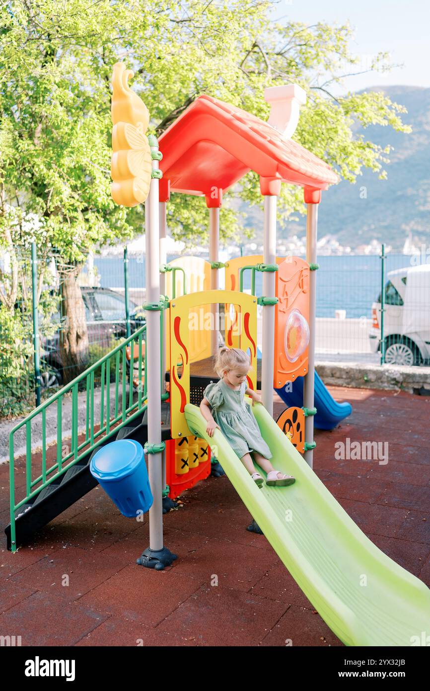 Little girl slides down a slide at a playground on the seashore Stock ...