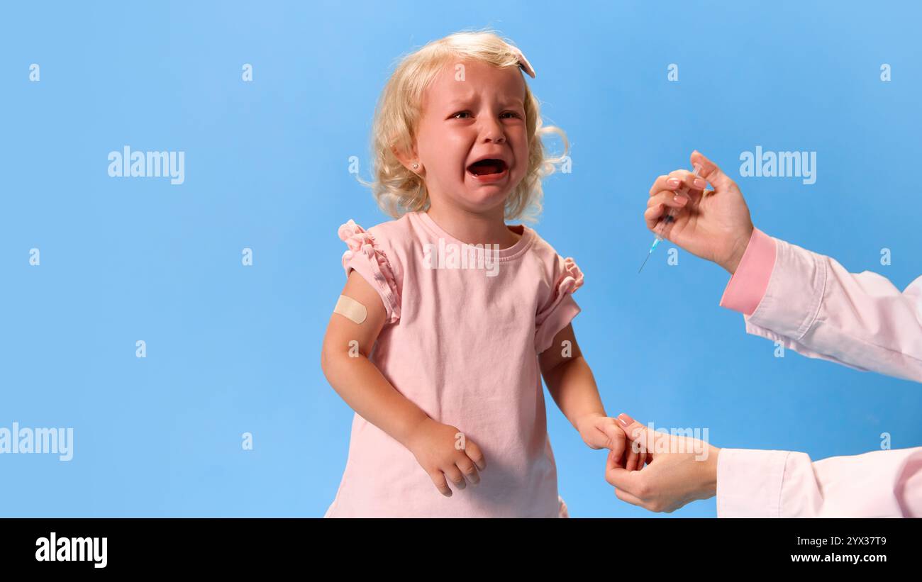 Doctor with doing vaccine injection to crying little girl against ...