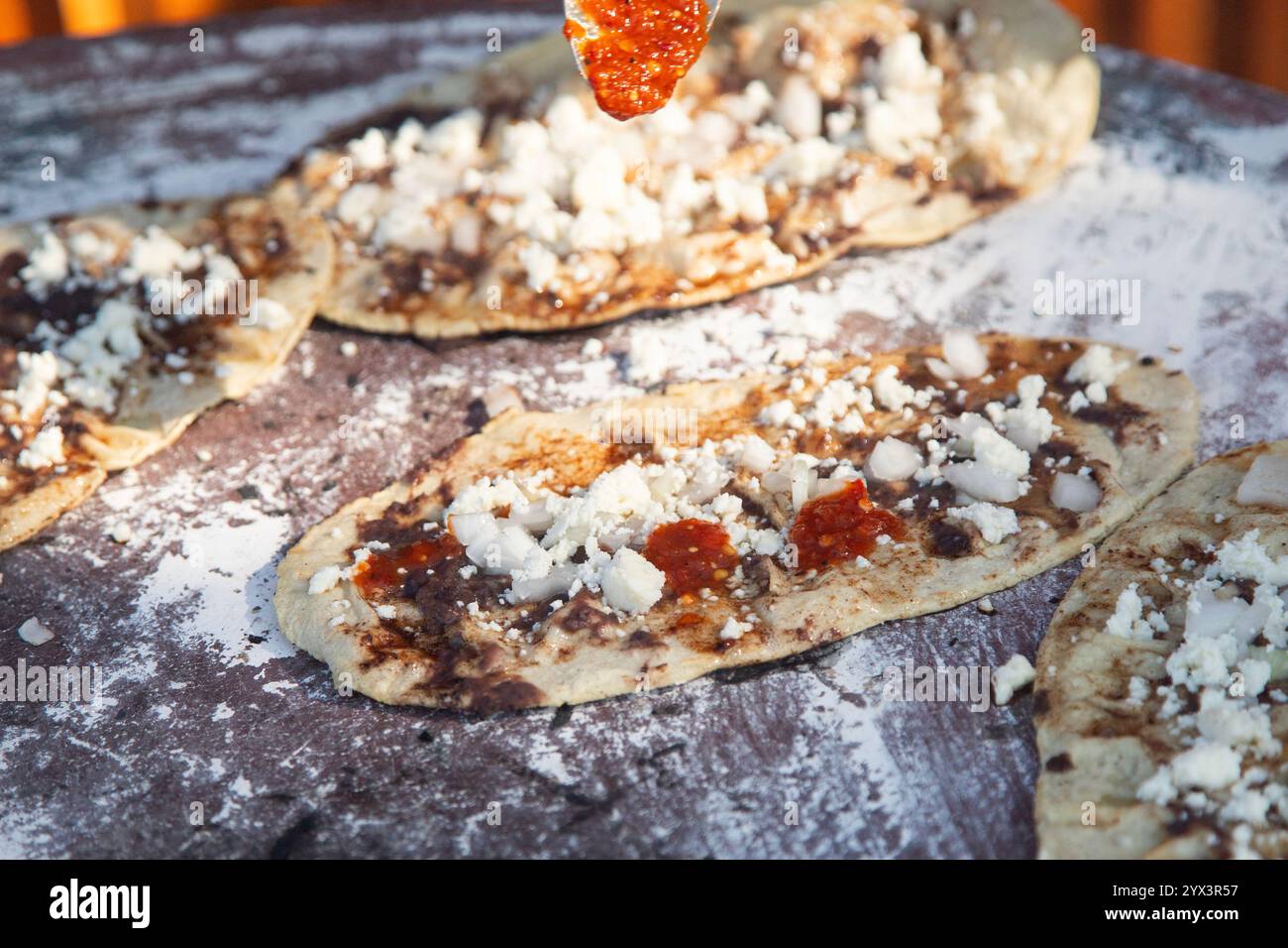 Memela or mamelita is a mexican oval tortilla, handmade with corn dough. They are thick and covered with bean paste and other ingredients. Stock Photo