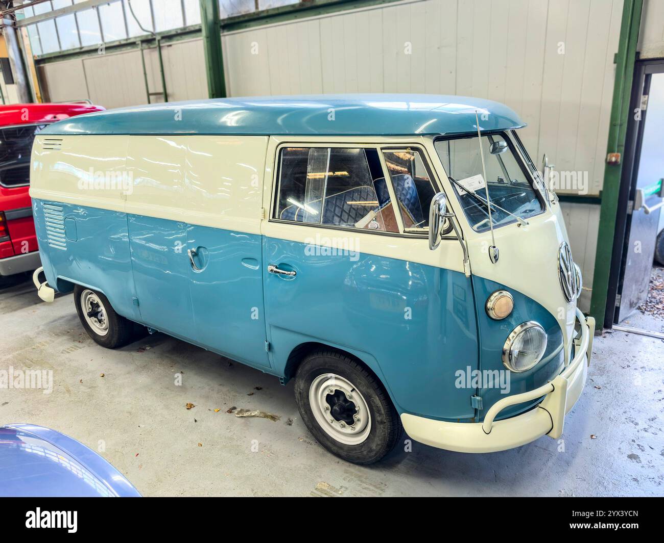 Classic turquoise and white vintage split screen VW volkswagen transporter van parked inside a garage, showcasing retro design and iconic style - Smartphone Captured Stock Image