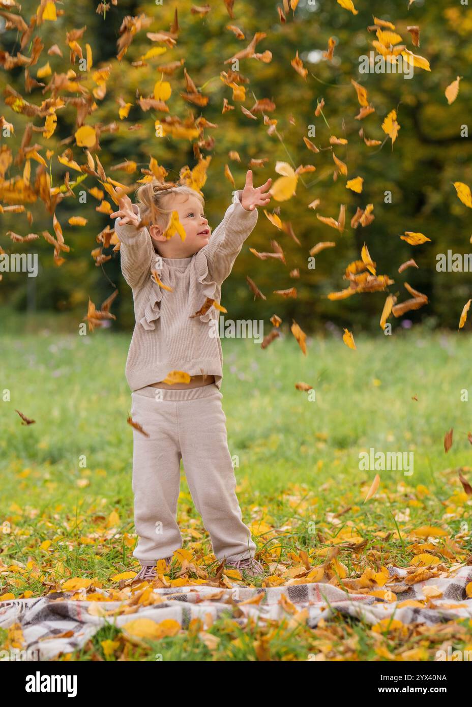 Cute little girl happily throwing yellow leaves in autumn park. Outdoors. Happy moments Stock Photo