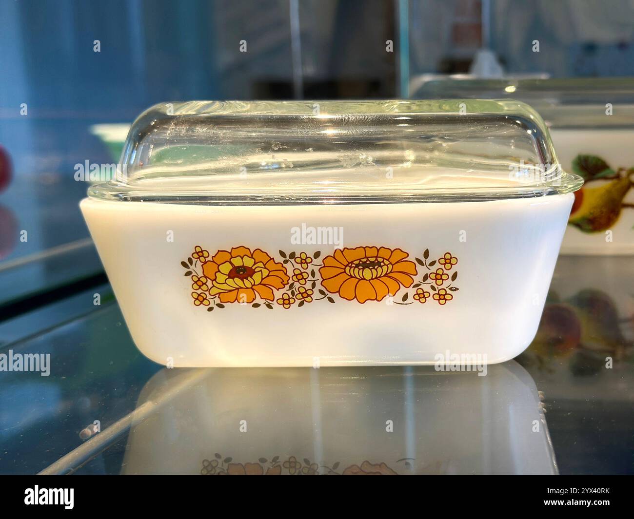 Vintage white Pyrex casserole dish with floral design and clear glass lid on reflective surface - Smartphone Captured Stock Image