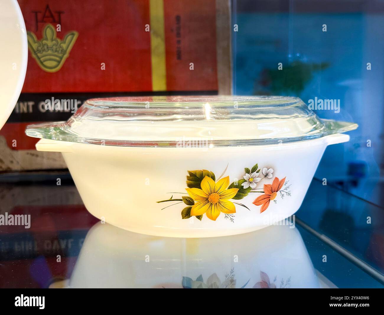 Vintage white Pyrex casserole dish with floral design and clear glass lid on reflective surface - Smartphone Captured Stock Image