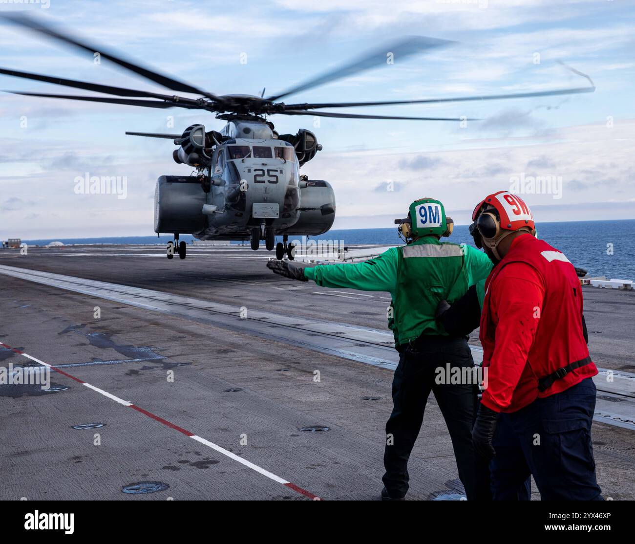 241210-N-SK738-1188 ATLANTIC OCEAN (Dec. 10, 2024) Sailors assigned to the Nimitz-class aircraft carrier USS George H.W. Bush (CVN 77) signal an MH-53 Stock Photo