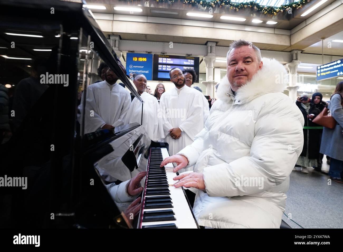 Former East 17 singer Tony Mortimer surprises commuters at St Pancras International station in London with a pop-up performance of his 1994 Christmas number one 'Stay Another Day', supported by the London Community Gospel Choir. The performance comes as Tony has partnered with the music therapy charity Nordoff and Robbins to celebrate the 30th anniversary of the song's release. Picture date: Friday December 13, 2024. Stock Photo