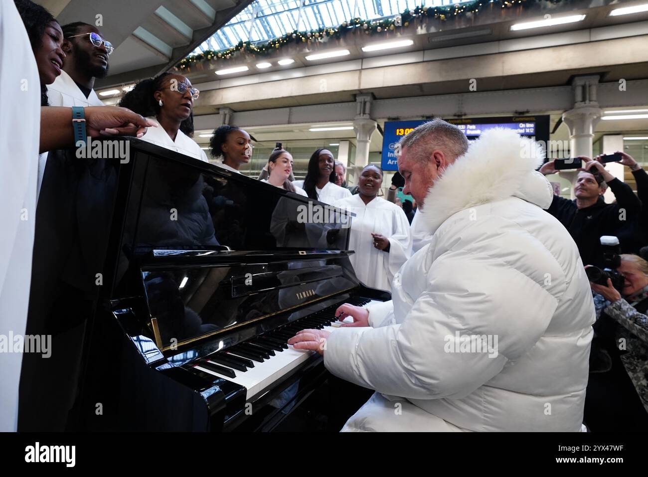 Former East 17 singer Tony Mortimer surprises commuters at St Pancras International station in London with a pop-up performance of his 1994 Christmas number one 'Stay Another Day', supported by the London Community Gospel Choir. The performance comes as Tony has partnered with the music therapy charity Nordoff and Robbins to celebrate the 30th anniversary of the song's release. Picture date: Friday December 13, 2024. Stock Photo