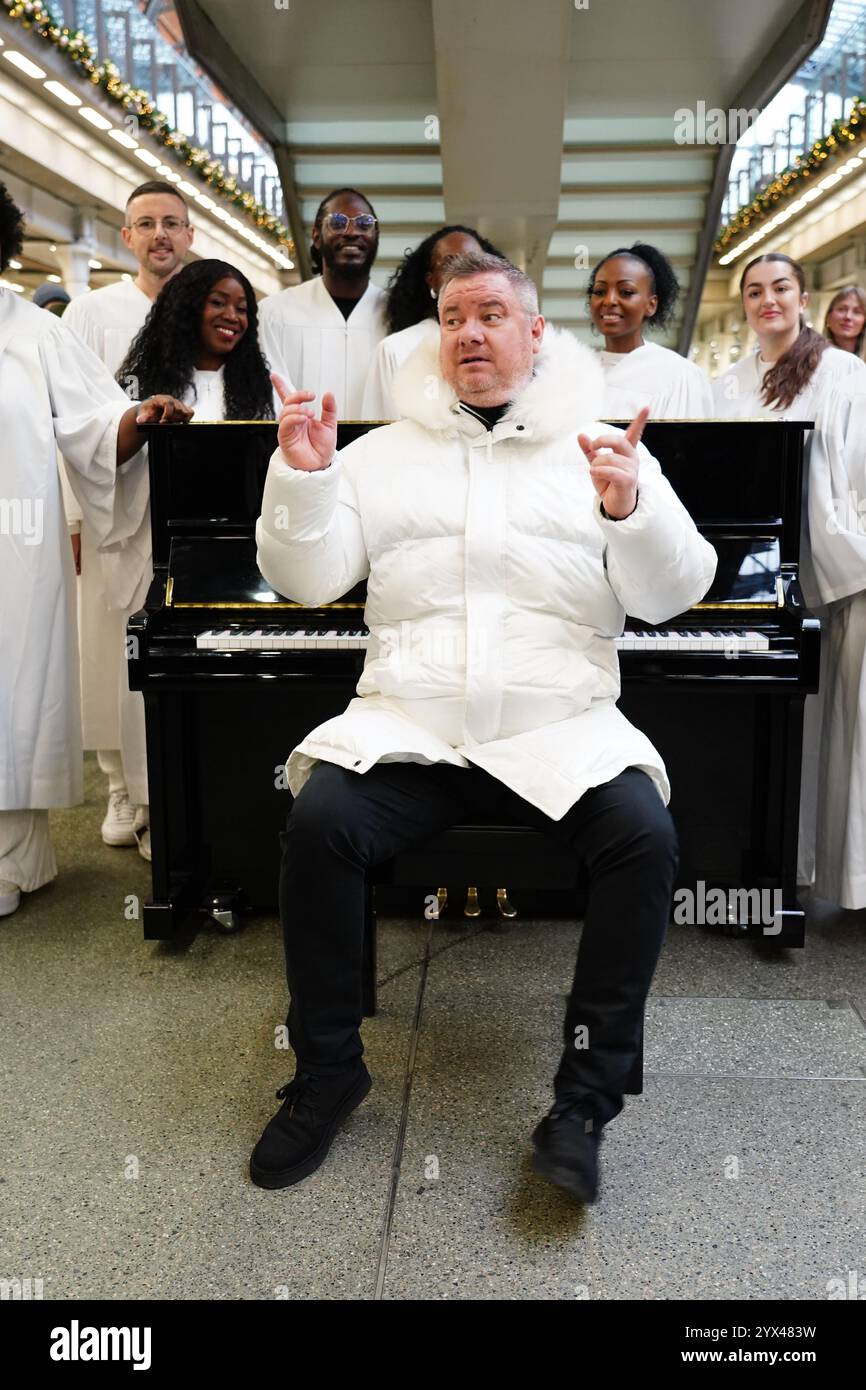 Former East 17 singer Tony Mortimer surprises commuters at St Pancras International station in London with a pop-up performance of his 1994 Christmas number one 'Stay Another Day', supported by the London Community Gospel Choir. The performance comes as Tony has partnered with the music therapy charity Nordoff and Robbins to celebrate the 30th anniversary of the song's release. Picture date: Friday December 13, 2024. Stock Photo