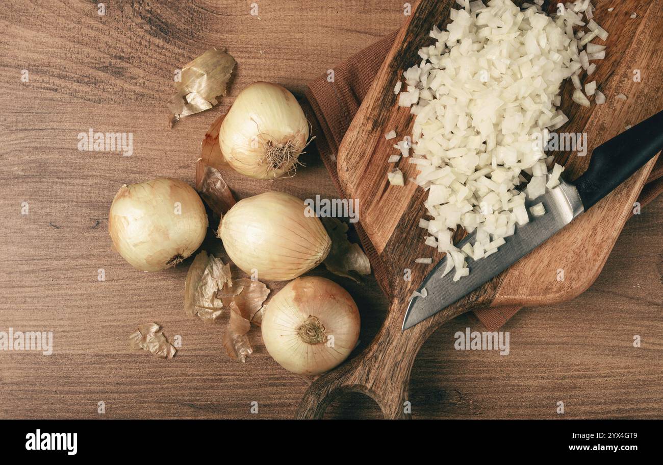 Finely chopped onion on a chopping board with a knife, wooden table ...