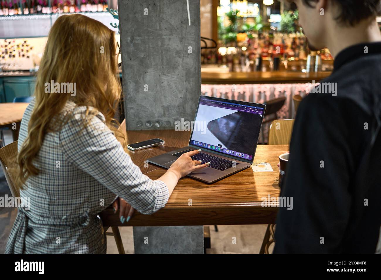 People in cafe having collaborative work session discussing project on laptop while enjoying coffee creative thinking concept Stock Photo