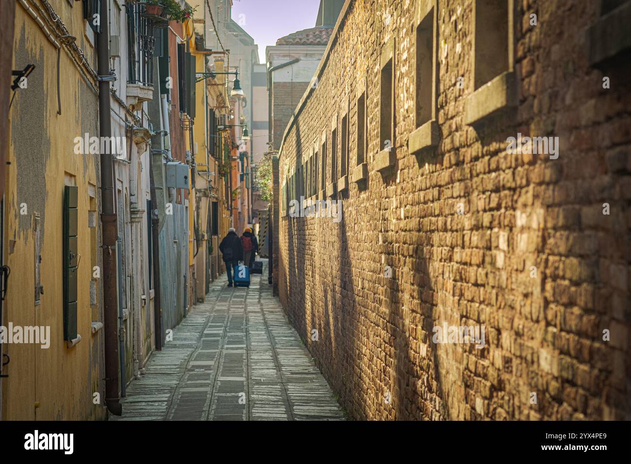 Venice, Italy. Tourists in a narrow alleyway looking for the door to their resort in Cannaregio, a historic district of the city. Stock Photo