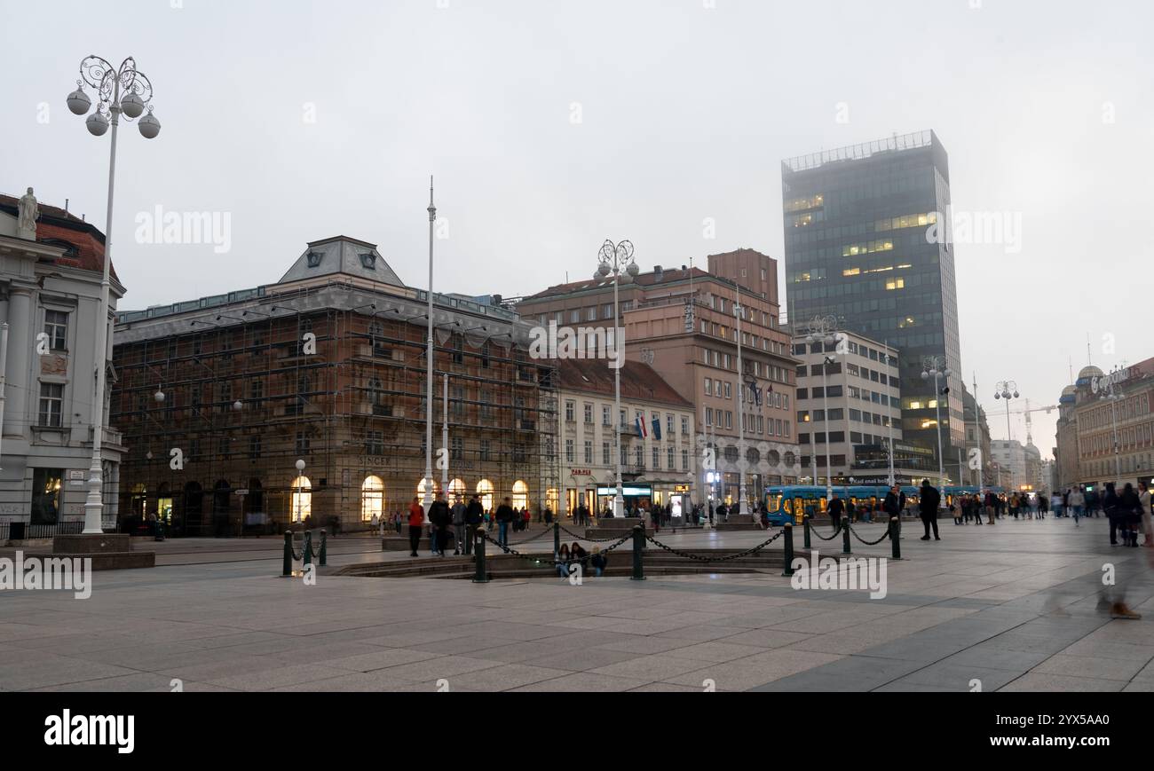 People walking and enjoying ban jelacic square in zagreb, croatia, with a tram passing by at dusk Stock Photo