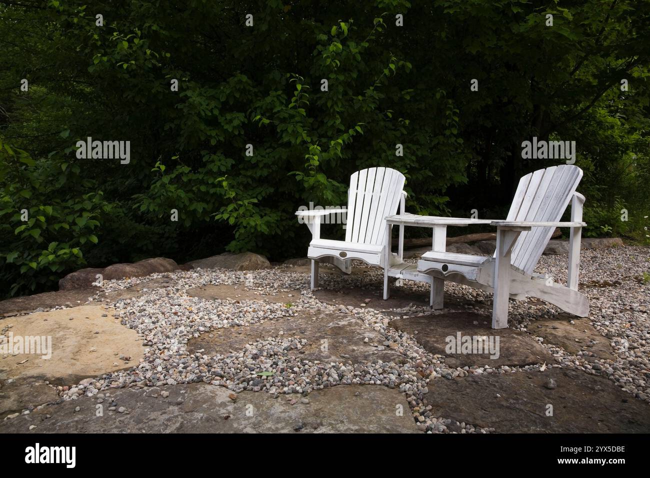 Pair of white wooden adirondack chairs on natural stone patio in front ...