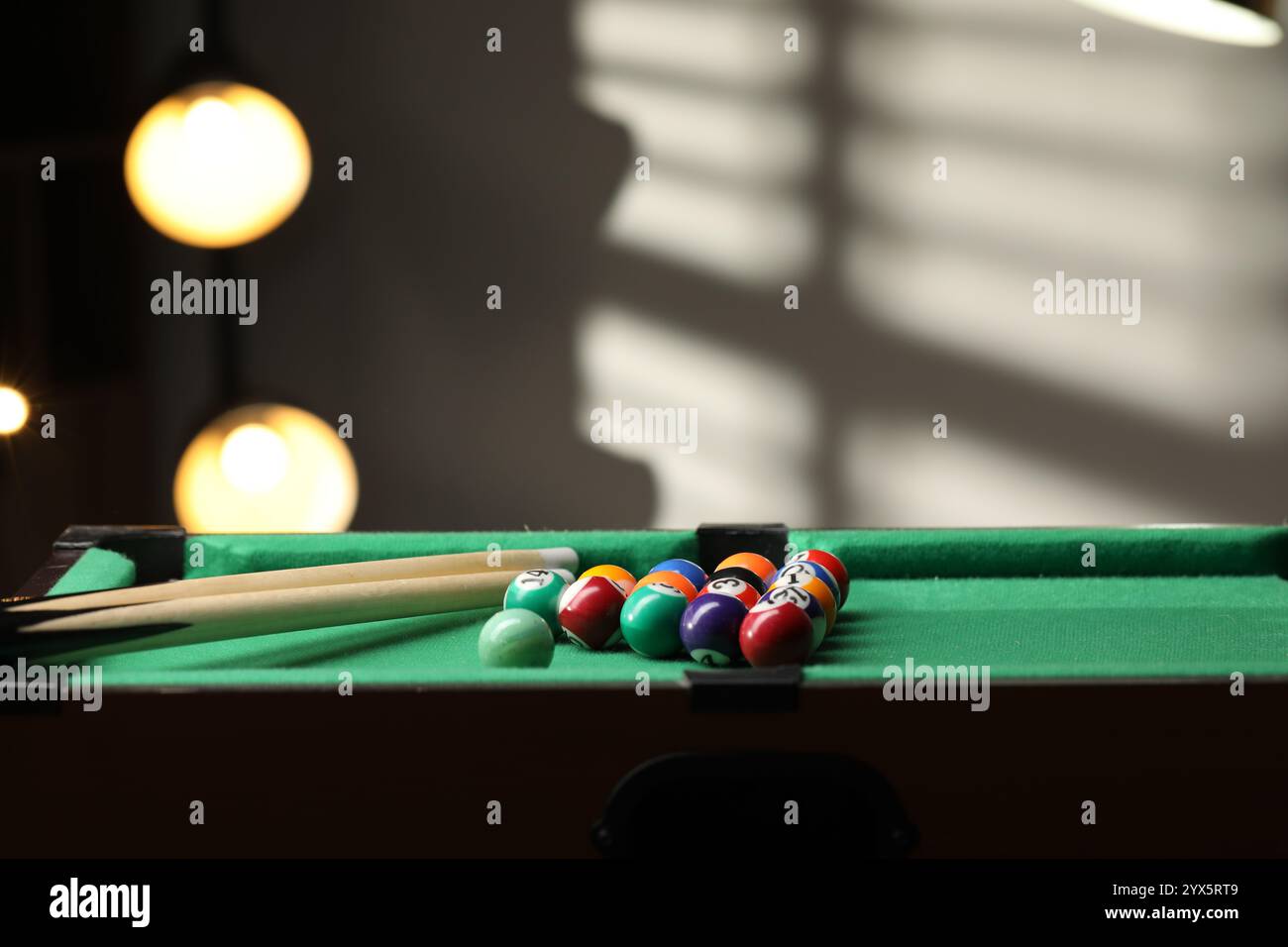 Billiard balls in triangle and cues on green table indoors. Space for text Stock Photo