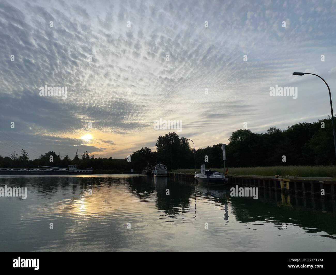 A sunset hidden in the clouds and boats standing by the water - Smartphone Captured Stock Image