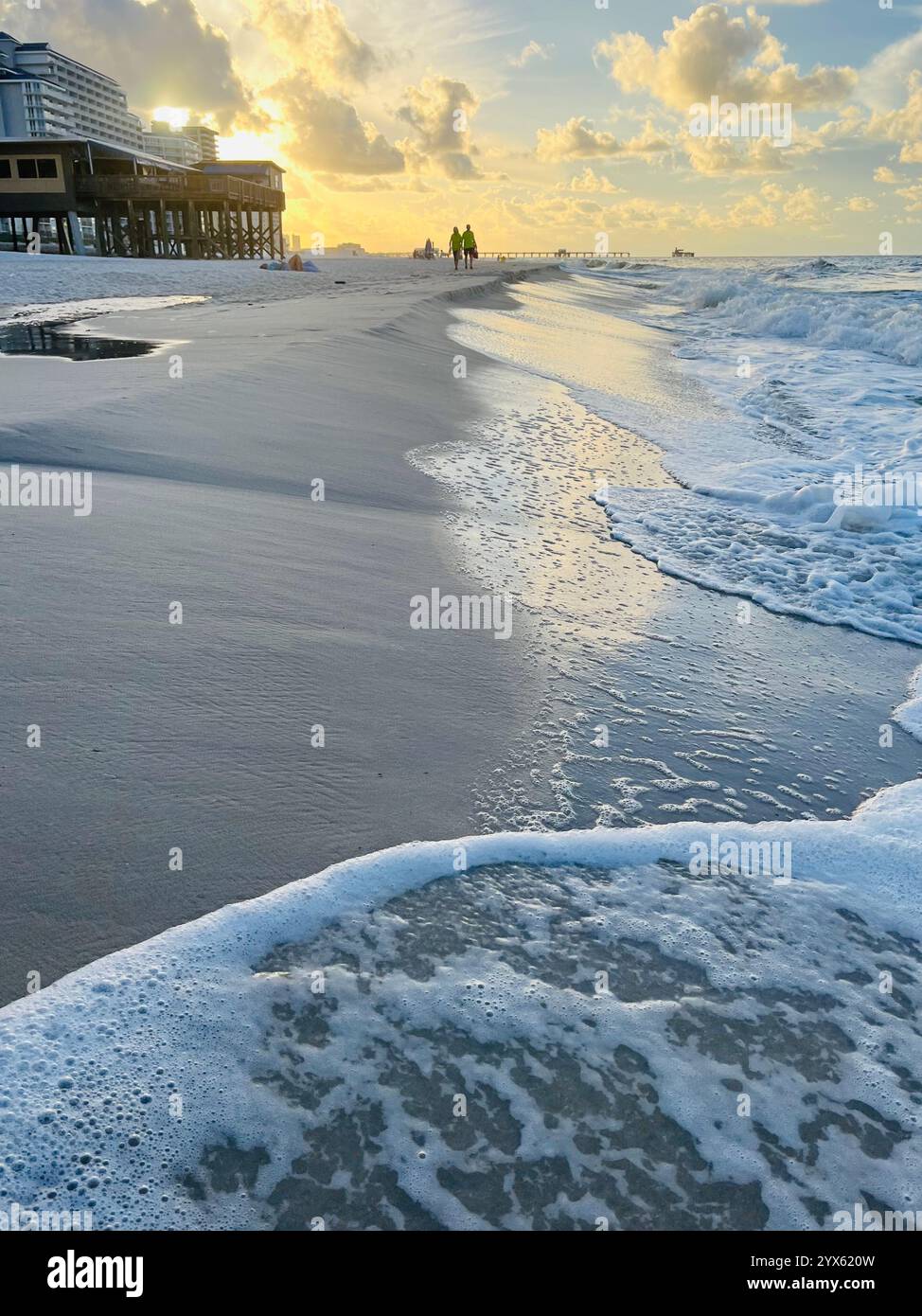 Golden Hour Beach Scene with Ocean Waves, Boardwalk, and People Walking Along the Shoreline - Smartphone Captured Stock Image