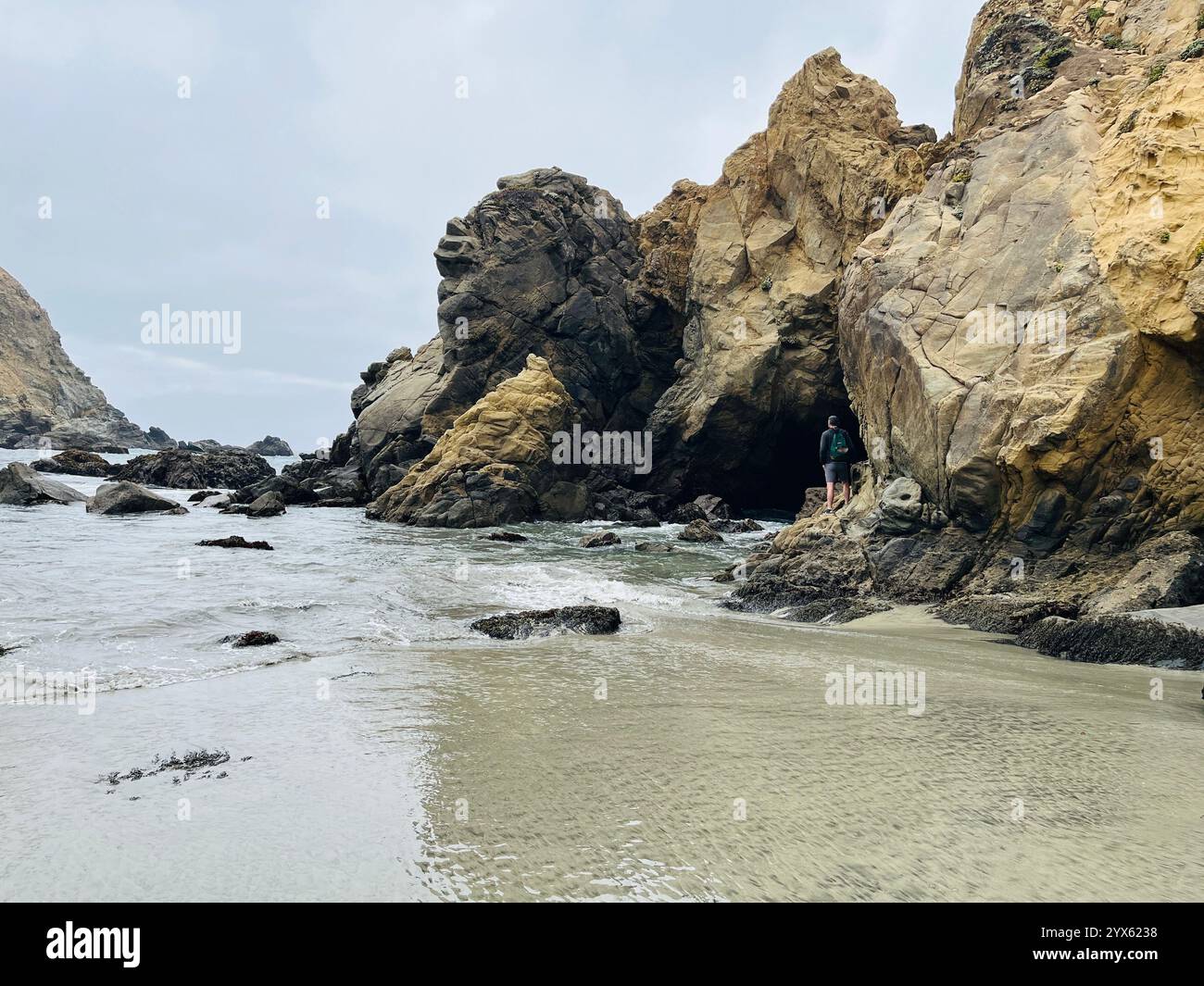 Solitary Explorer by Coastal Rock Formations on a Cloudy Day - Smartphone Captured Stock Image