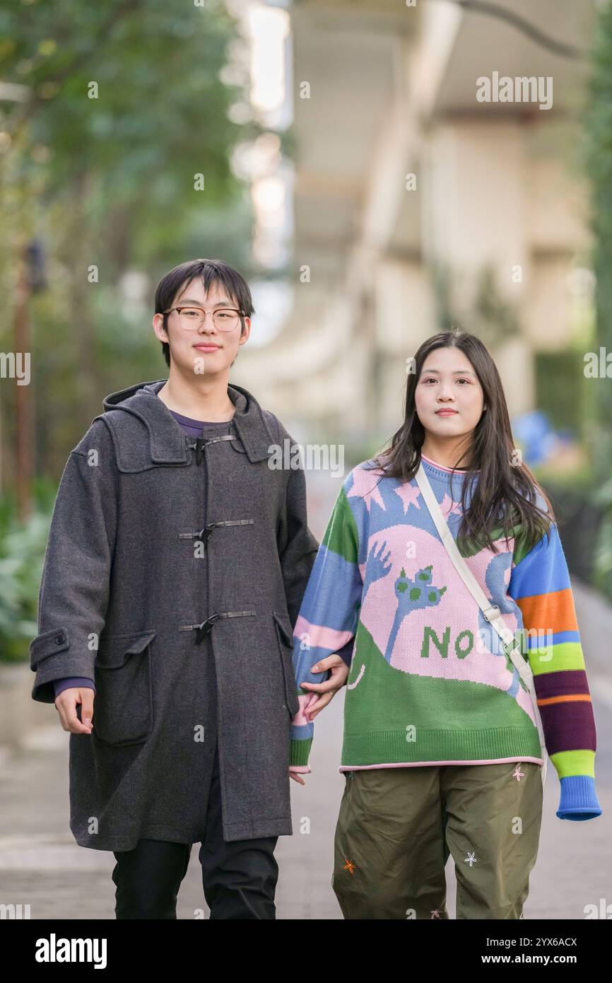 Young Chinese couple in their 20s standing on sidewalk in Hongkou District, Shanghai, People's Republic of China during cold season in December 2024. Stock Photo