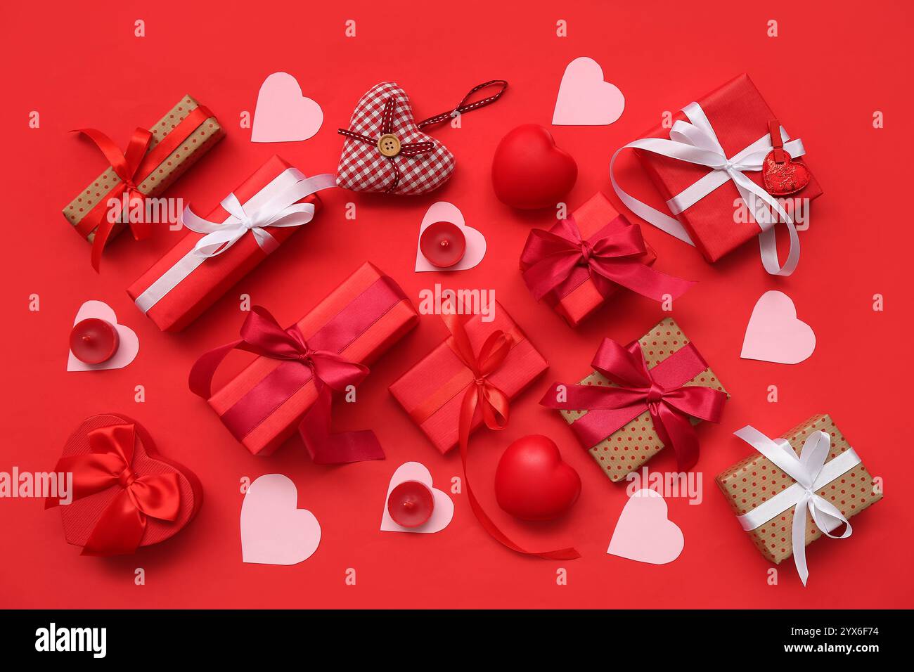 Gift boxes with paper hearts and candles on red background. Valentine's Day celebration Stock Photo