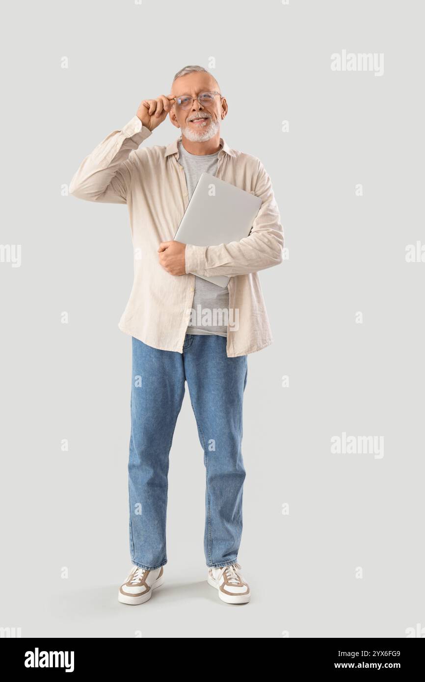 Mature programmer with laptop on light background Stock Photo
