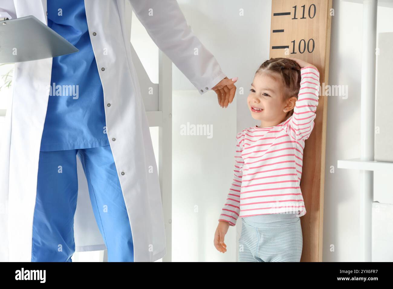 Female pediatrician with cute little girl measuring height near ...