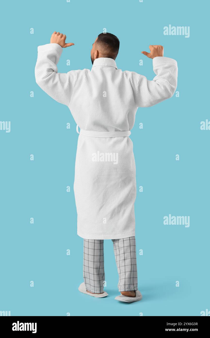 Young man in robe on blue background. Back view Stock Photo